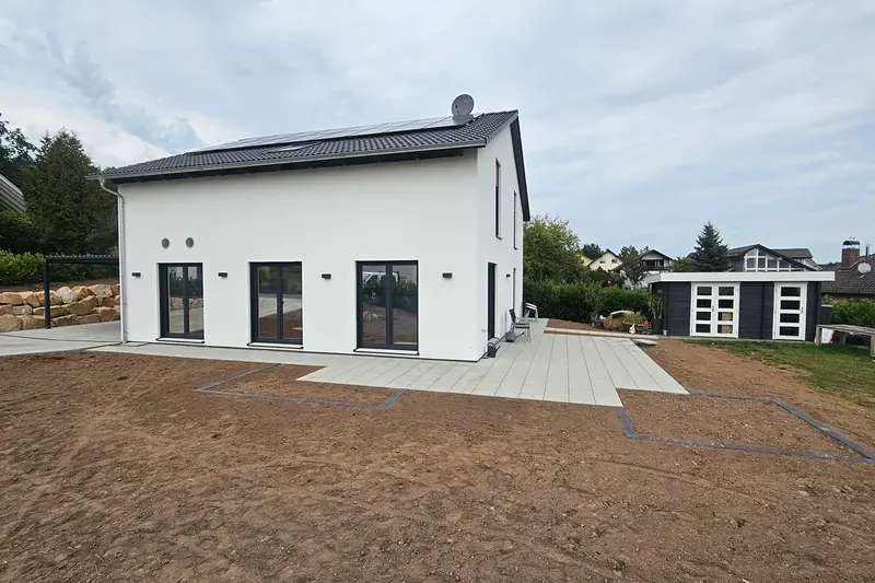 Gartenseite des Neubaus mit Terrasse aus großen hellen Platten