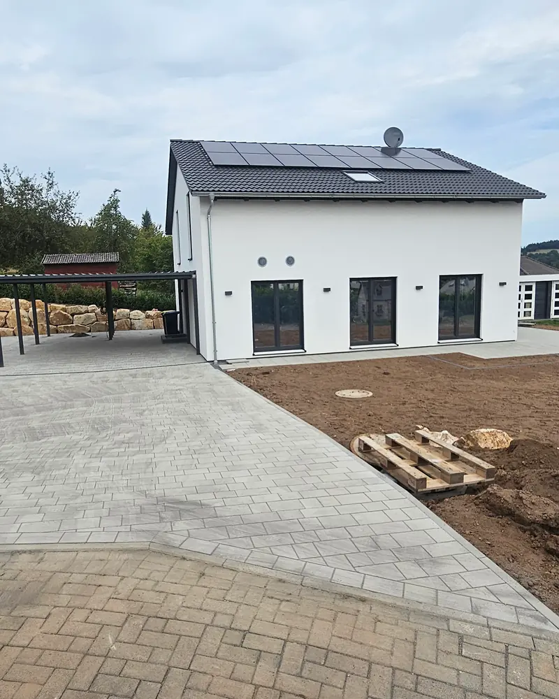 Neubau mit gepflasterter Einfahrt, Carport und Mauer aus Natursteinblöcken