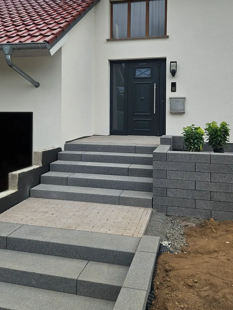 Eingangstreppe in zwei Läufen mit Podest, rechts die Mauer aus Mauersteinen