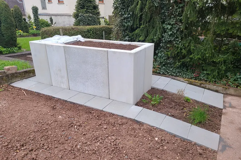 Hochbeet aus Betonelementen mit einem Weg aus Platten
