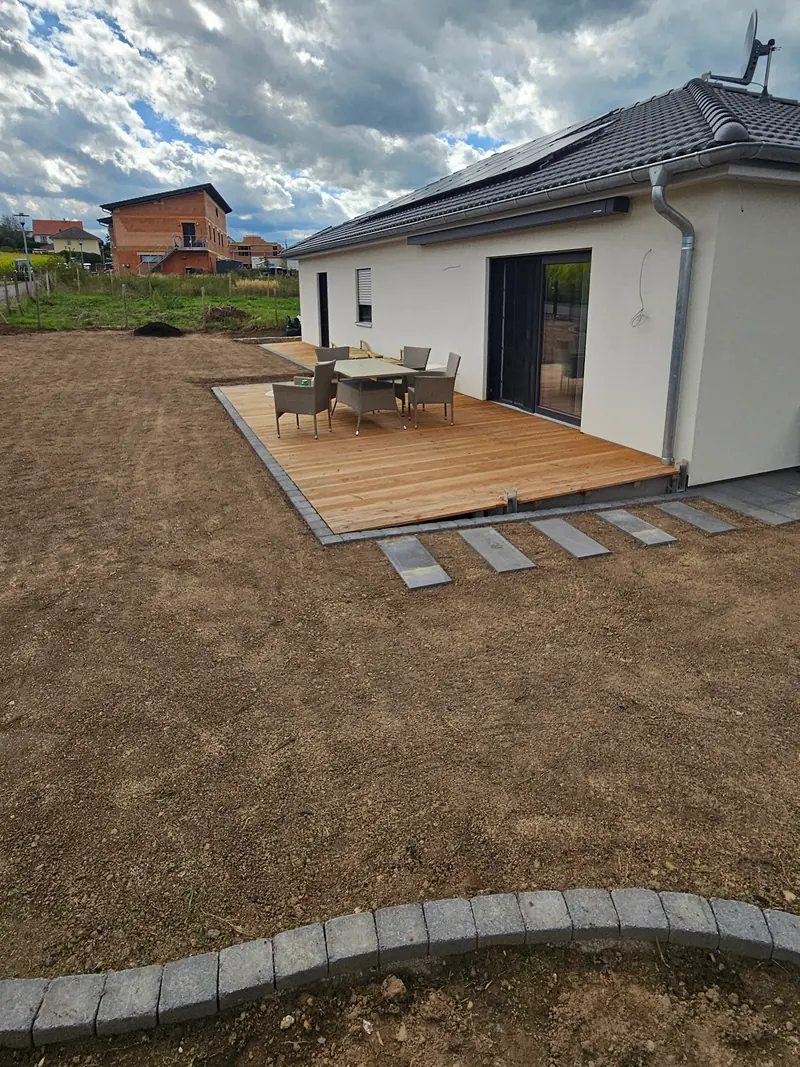 Holzterrasse am Bungalow mit Sitzgruppe, Trittplatten und geschwungener Rasenkante