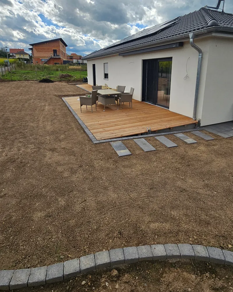 Holzterrasse mit Sitzgruppe an einem Bungalow, davor Trittplatten