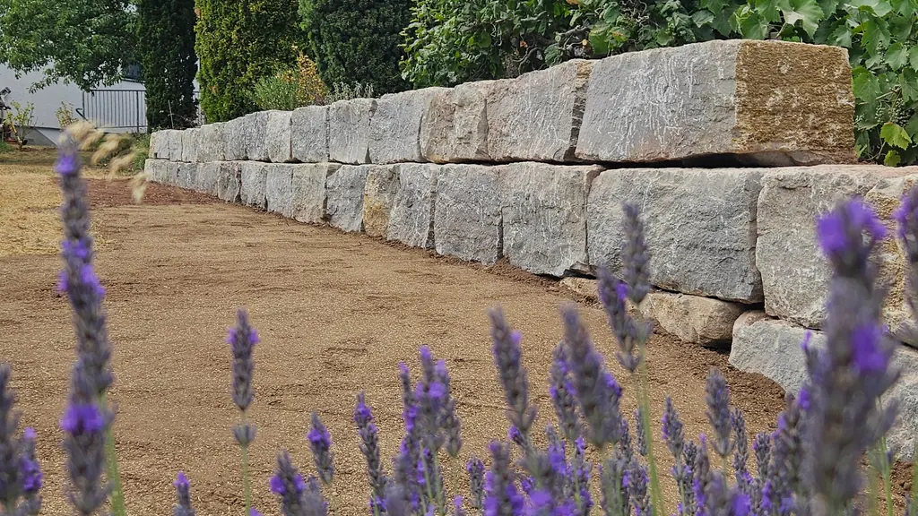 Mauer aus Natursteinblöcken, im Vordergrund blühender Lavendel