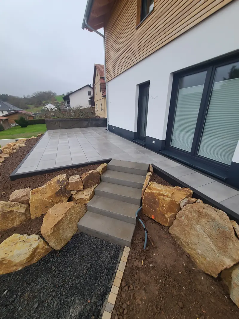 Blockstufen zwischen großen Natursteinen hinauf zur Terrasse
