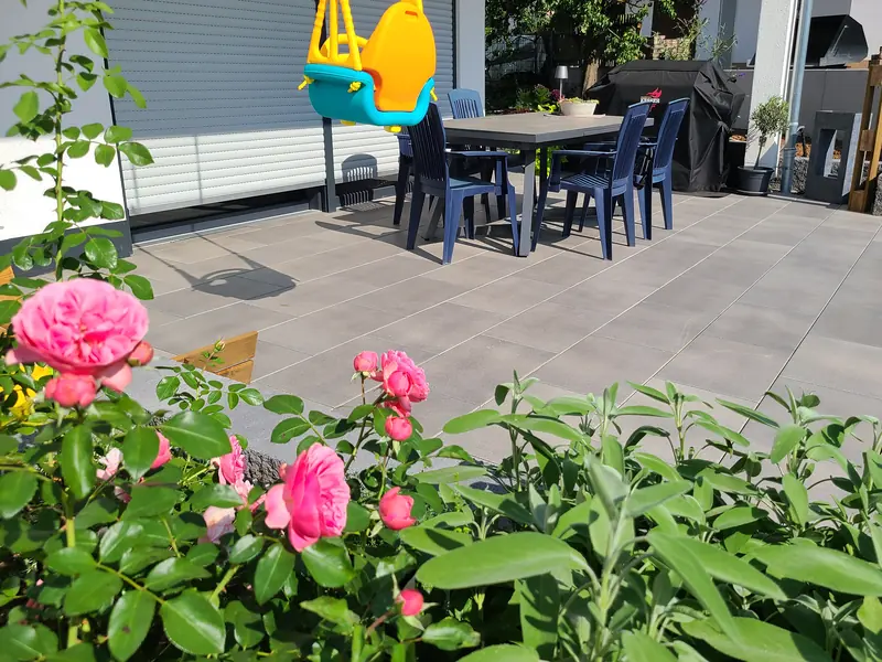 Terrasse aus Großformatplatten, im Vordergrund blühende Rosen