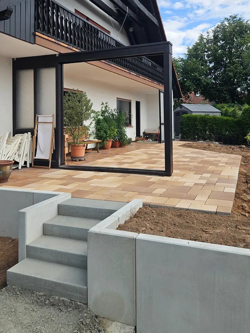 Terrasse am Haus mit Pergola, davor die Treppe aus Blockstufen