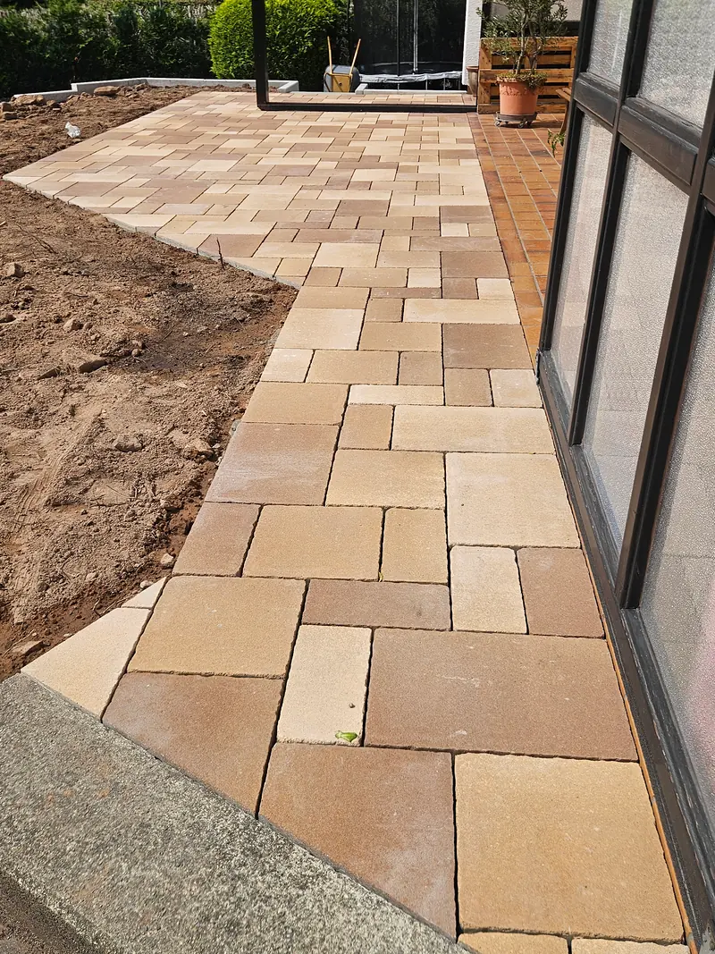 Pflaster in Sand- und Terrakottatönen entlang der Hauswand