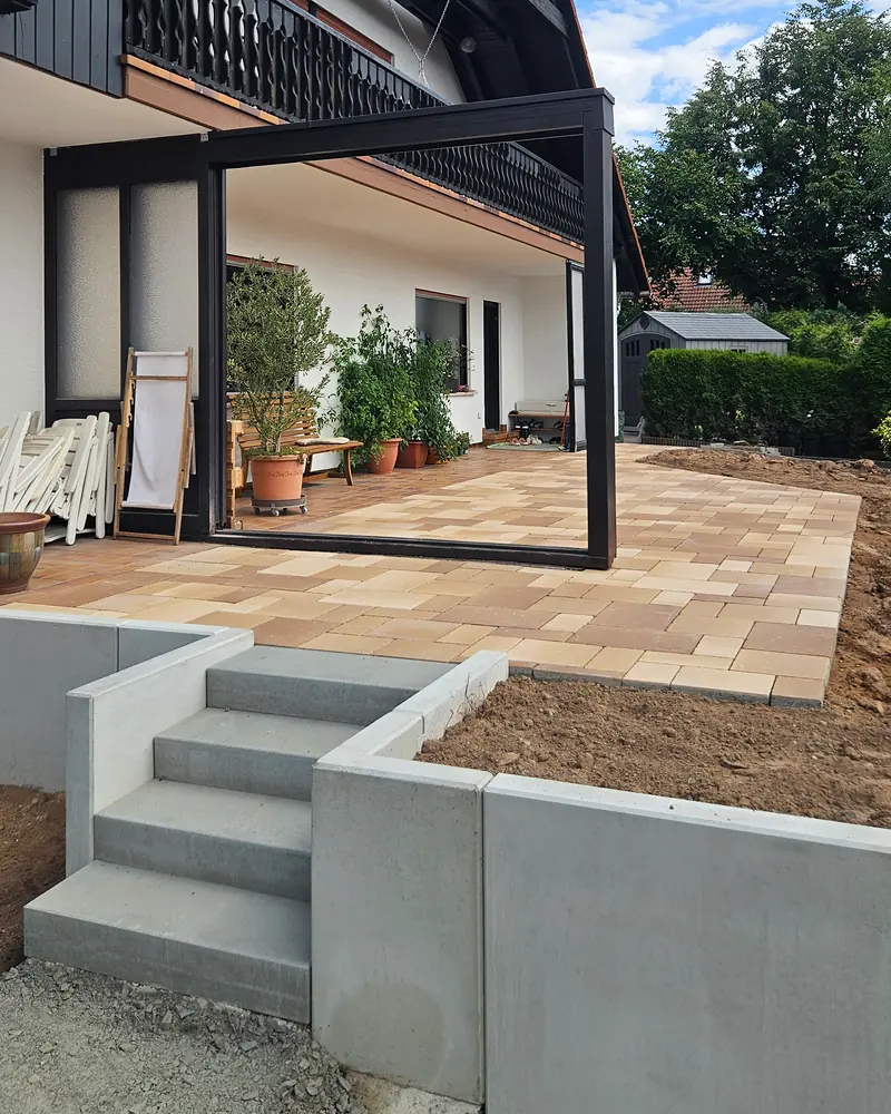 Terrasse aus Pflaster in warmen Farbtönen mit Treppe aus Blockstufen und Winkelsteinen