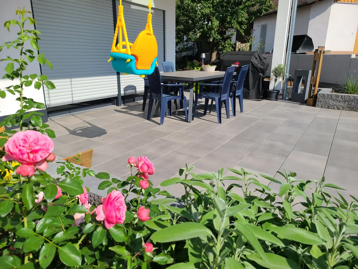 Terrasse aus Großformatplatten mit Rosen im Vordergrund