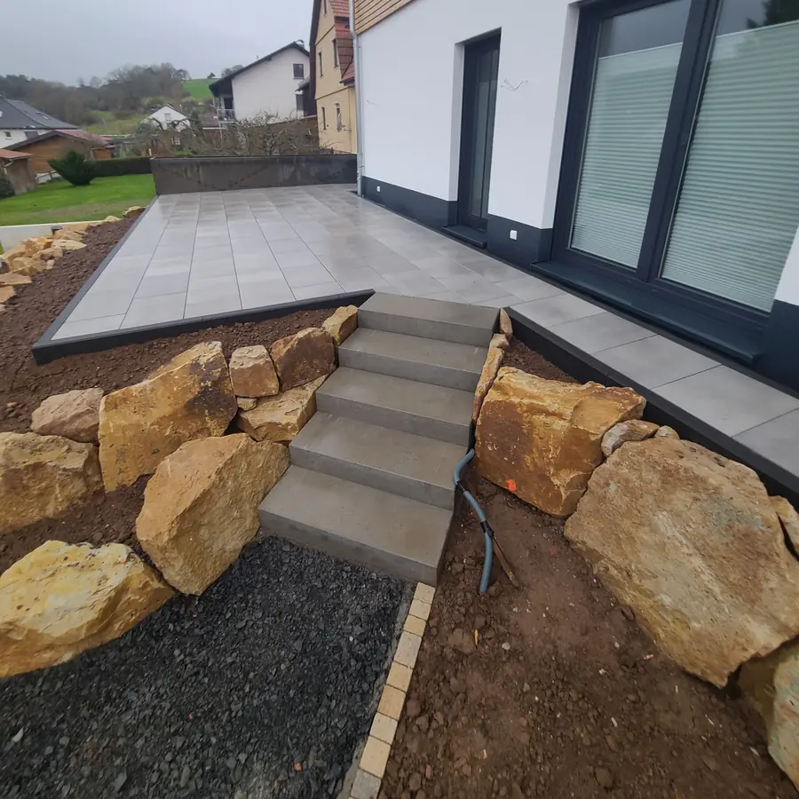 Stufen zwischen großen Natursteinen hinauf zur Terrasse
